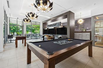 a games room with a pool table and two televisions